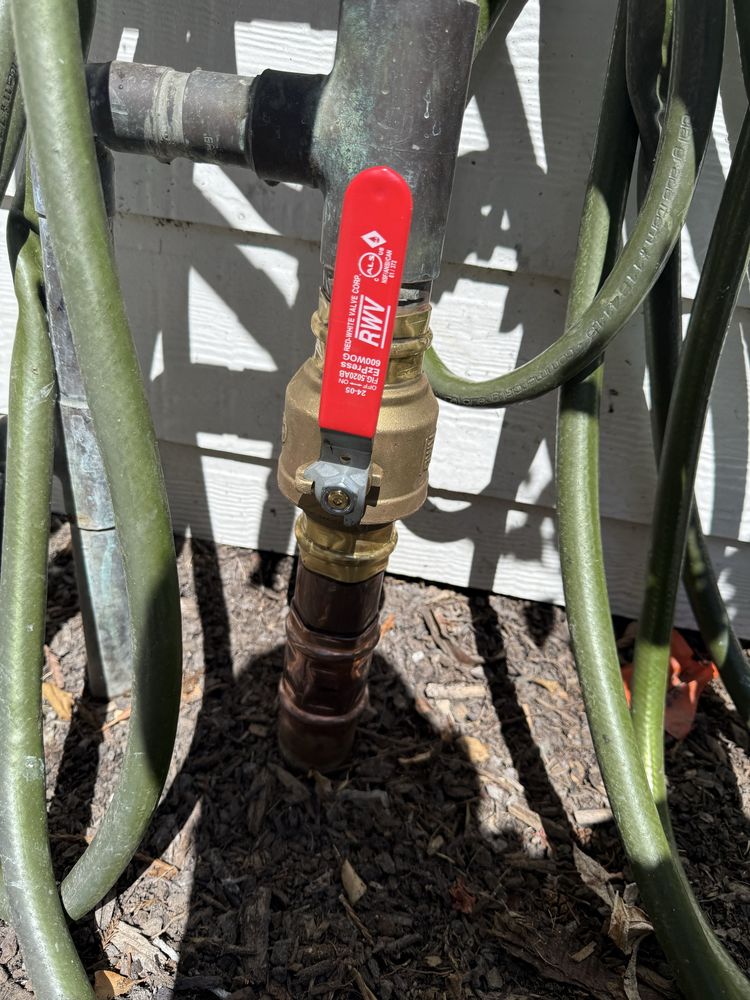 Outdoor backflow preventer assembly with red shutoff handle installed on a commercial water line