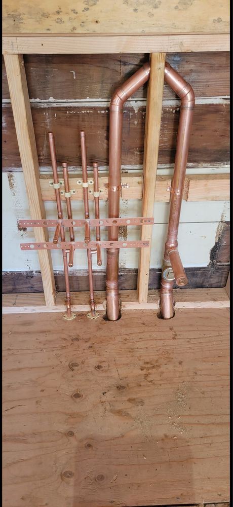 Copper pipe rough-in stub-outs mounted on wall framing during a commercial plumbing installation